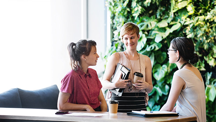 three coworkers talking at breakout area(background sustainability view)