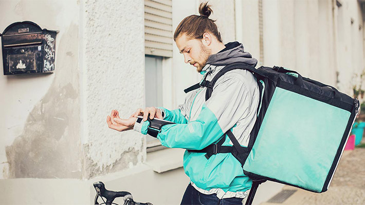 Side view delivery man carrying parcel on a bike