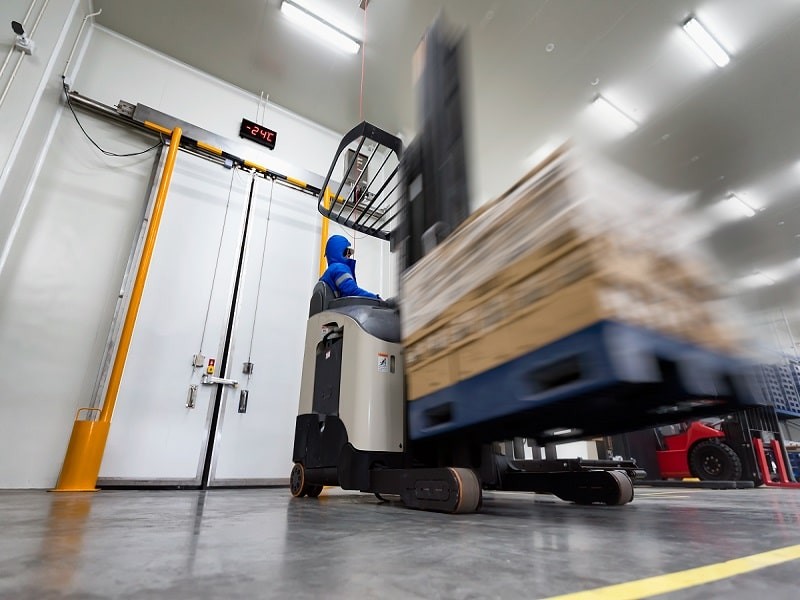 Blurred view of worker using machine to lift the stocks in the warehouse