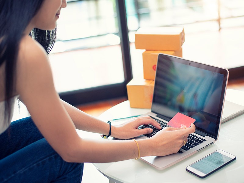 Young woman paying shopping online with a credit card at home