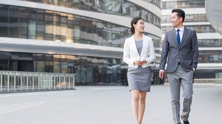Two business professionals walking outside the office building and discussing the new project