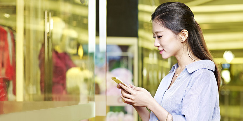 young asian woman with a cellphone at shopping mall