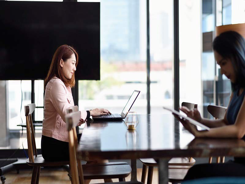 Side view of coworkers working on laptops while seated in modern office chairs