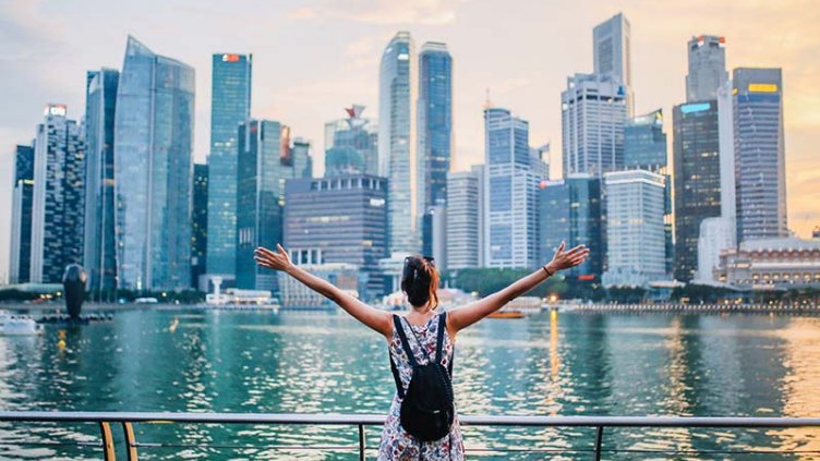 A picture of a woman overlooking a river with Singapore’s skyline in the backdrop