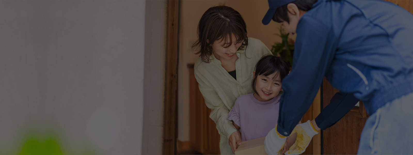 Smiling young woman and her daughter receiving delivery from delivery man at home