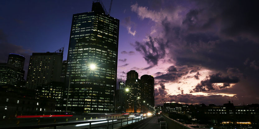 Office buildings are seen illuminated against a purple sky in Sydney’s central business district