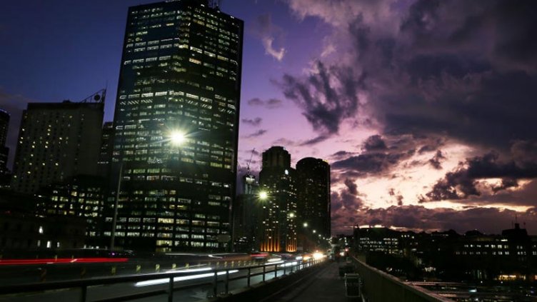 Office buildings are seen illuminated against a purple sky in Sydney’s central business district