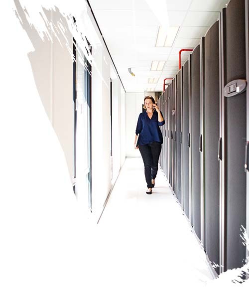 Businesswoman talking on smart phone while walking in office corridor