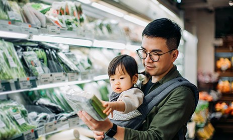 Men checking the price tag for vegetables in grocery store