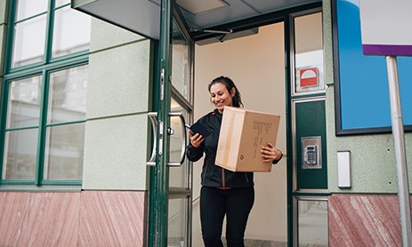 Smiling woman using cell phone while receiving home delivery