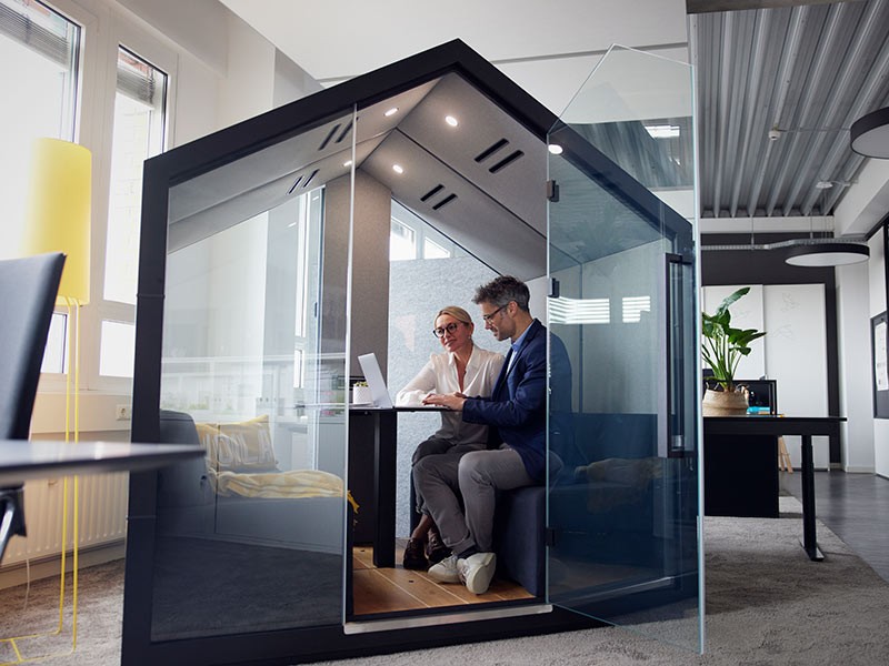 Colleagues working on laptop sitting in office cubicle