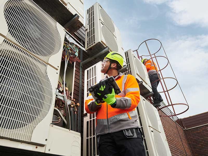 Maintenance engineers inspecting HVAC air conditioning units on a roof