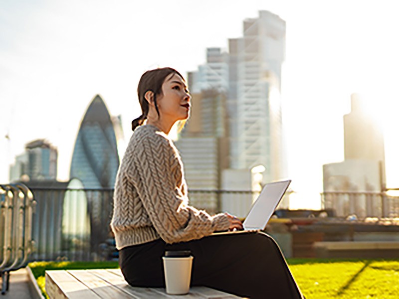 Young woman with laptop working on roof terrace