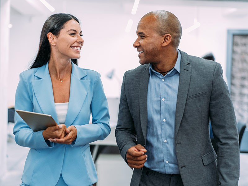 Male and female business colleagues in mentoring partnership discussing workplace strategies