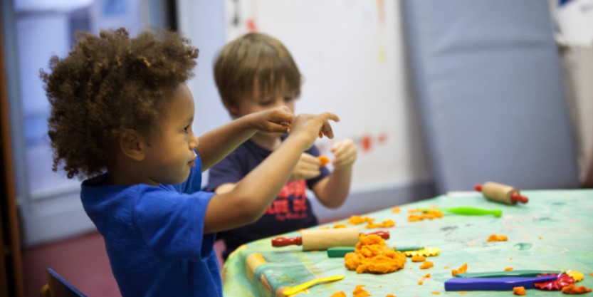 children sitting on chair and doing activity with toys on table