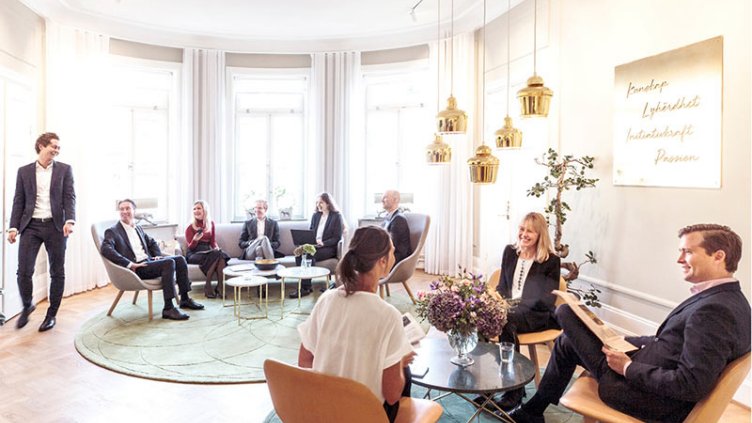 Employees sitting and interacting in office common area at workplace.